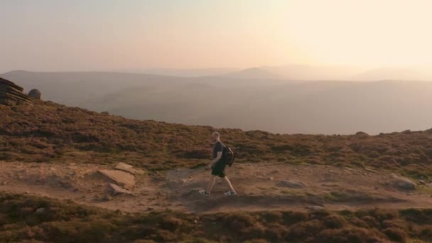 Aérienne - Suivre un jeune mâle grimpant le long d'une magnifique colline au coucher du soleil
 - Séquence, vidéo
