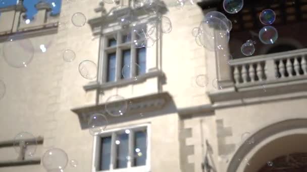 Vielgestaltige Seifenblasen fliegen im Sommer am historischen Haus am Krakauer Platz - Filmmaterial, Video