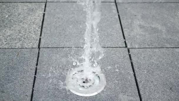 Vrolijke waterstroming oprijzen en vallen op een fontein gat in een grijze plaat - Video