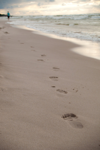 Jalanjälkiä märkää hiekkaa rannalla
 - Valokuva, kuva