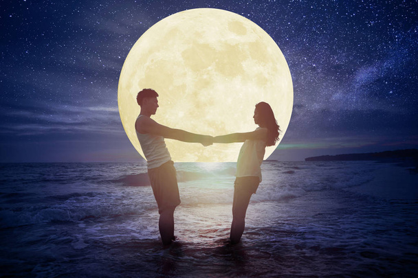 jeune couple debout sur la plage et regarder la lune.Célébrer M
 - Photo, image