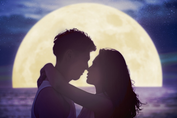若いカップルはビーチでキスをし、月を見て。ミを祝う - 写真・画像