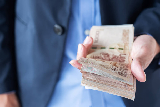 Бизнесмен держит стопку банкнот Тай Бат. бизнес, мес
 - Фото, изображение
