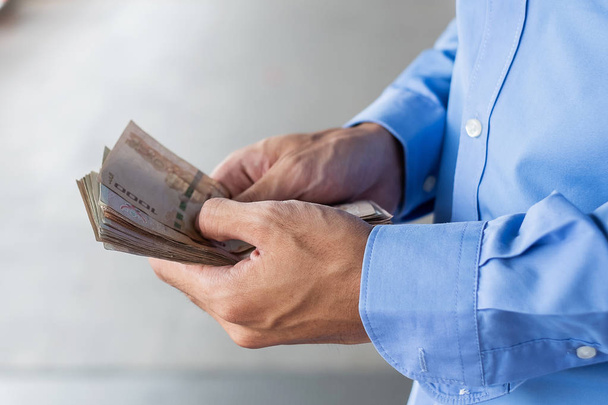 Przedsiębiorca ręka trzyma tajski Baht banknotów stosu. biznes, pon - Zdjęcie, obraz