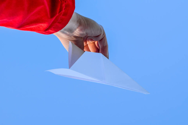 White paper airplane in hand against the sky. A symbol of freedom on the Internet - 写真・画像