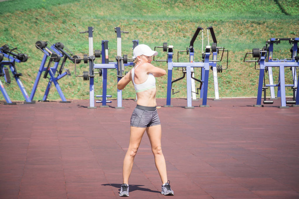 A young sports girl doing a warm up in the summer or autumn park - Foto, Bild