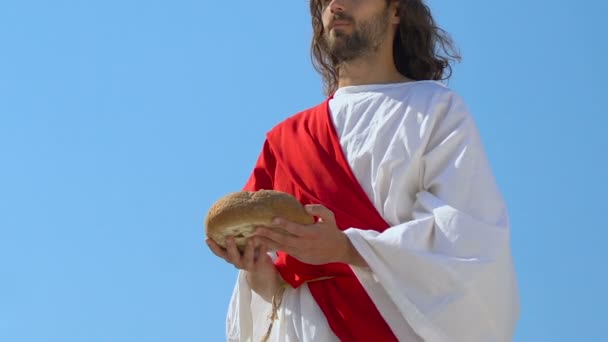 Jesus in robe and sash raising bread to heaven, asking God for blessing food - Footage, Video