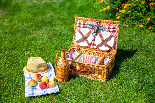 Корзина для пикника на зеленом солнечном газоне в парке
 - Фото, изображение
