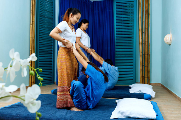 Two thai masseuses synchronously doing thai massage. - Photo, Image