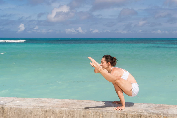 Mujer caucásica en traje blanco practicando yoga en la playa
 - Foto, Imagen