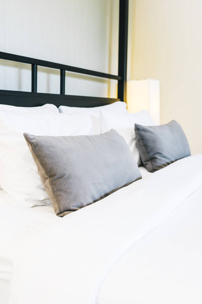 schönes luxuriöses bequemes Kissen auf dem Bett mit Lampe - Foto, Bild