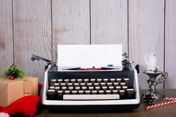 Retro typewriter with a blank sheet of paper for text. White New Year and Christmas Background Mock up, Copy space with gifts and a candle. - Photo, image