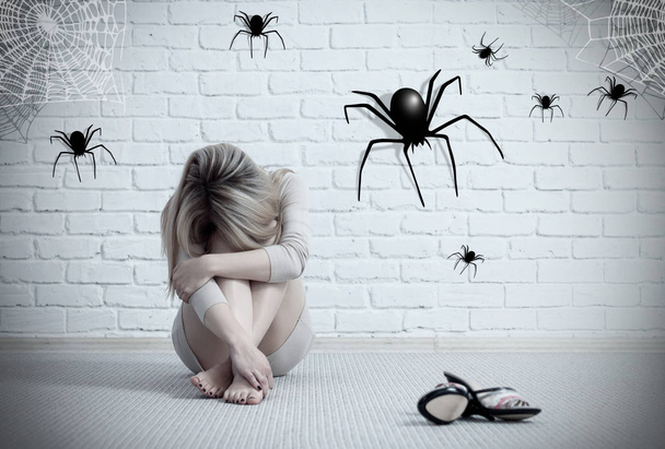 Woman sitting on the floor and looking on imaginary spider. - Photo, Image
