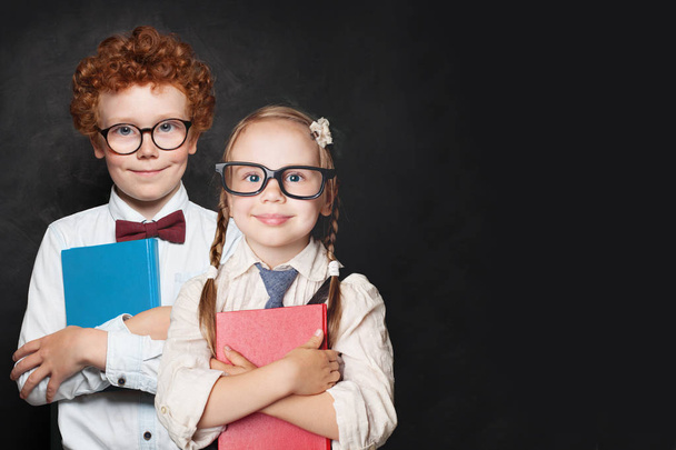Happy kids pupils in glasses holding books on chalkboard background - Fotografie, Obrázek
