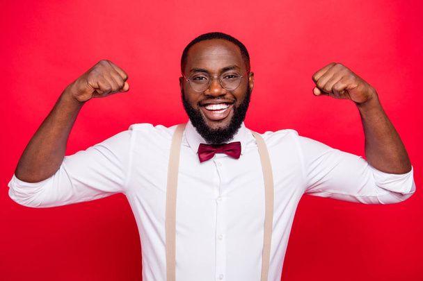 Photo of dark skin guy showing big biceps wear specs white shirt isolated red background - Foto, immagini