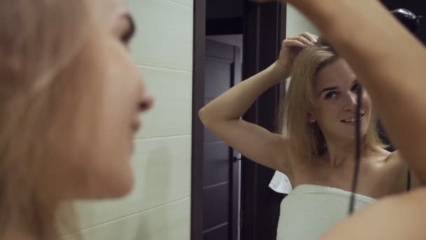 Piękna kobieta Suszenie włosów z suszarką szczoteczką po wzieniu prysznica w łazience. - Materiał filmowy, wideo