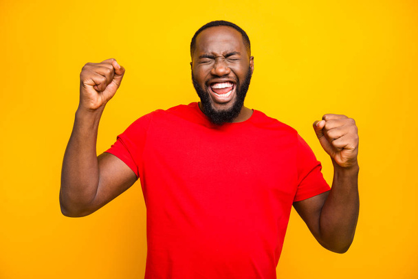 Photo of bearded overjoyed ecstatic man having won some competitions while isolated with yellow background - Photo, Image