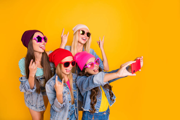 Close-up photo of cool carefree charming nice ladies showing tongue-out heavy metal symbols small photographer taking self picture of fellow friendship group people isolated yellow background - 写真・画像