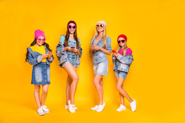 Full length photo of four nice positive cool millennials using modern technology following stars users on social network browsing reading news isolated yellow background - Фото, зображення