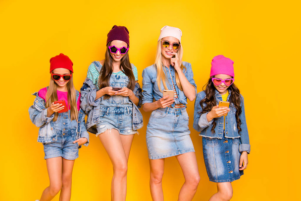 Photo of four cheerful positive flirty mother and daughter mom blonde brunette and teen babies using digital gadget devices receiving likes and comments isolated bright background - Фото, зображення