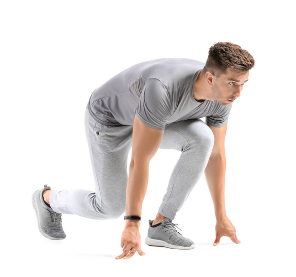 Urheileva nuori mies crouch aloituspaikka valkoisella taustalla
 - Valokuva, kuva