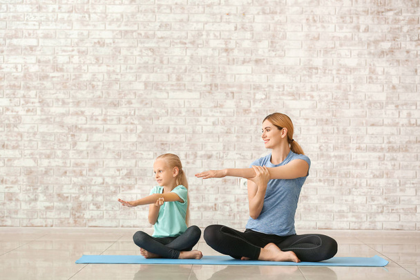 Mother with little girl doing yoga indoors - Foto, afbeelding