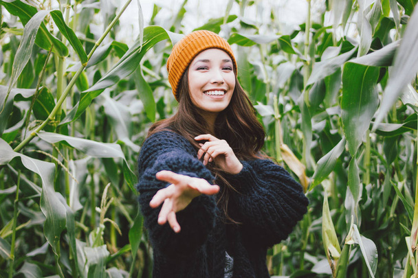Sarı şapka ve sonbahar mısır alanında örme kazak güzel kaygısız uzun saçlı asya kız. Doğa kavramına duyarlılık - Fotoğraf, Görsel