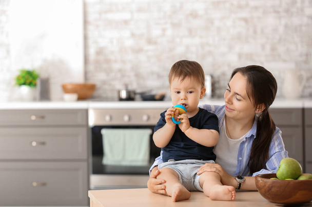 Mãe e seu filhinho com mordedor na cozinha em casa
 - Foto, Imagem