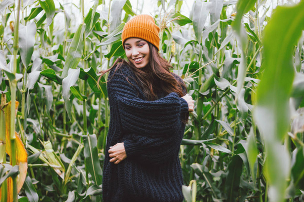 黄色い帽子と秋のトウモロコシ畑でニットセーターで美しい気楽な長い髪のアジアの女の子。自然概念に対する感受性 - 写真・画像