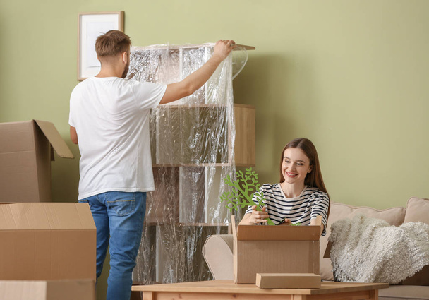 Young couple unpacking things after moving into new house - Photo, Image