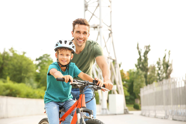 Père enseignant à son petit fils à faire du vélo à l'extérieur
 - Photo, image
