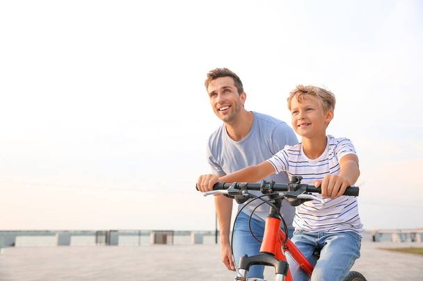 Ojciec uczy swojego syna, aby jeździć na rowerze na zewnątrz - Zdjęcie, obraz
