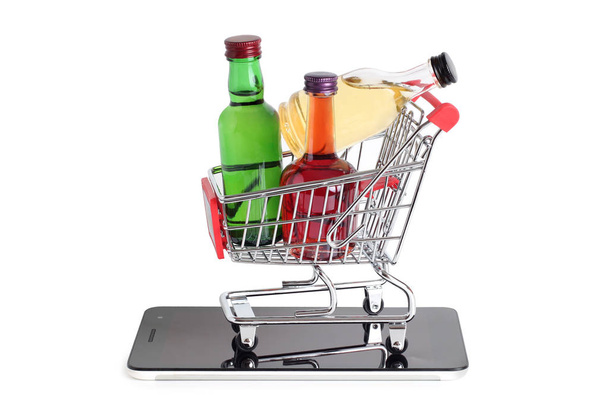 Metal cart whit bottle from store and smartphone on a white background - Фото, зображення