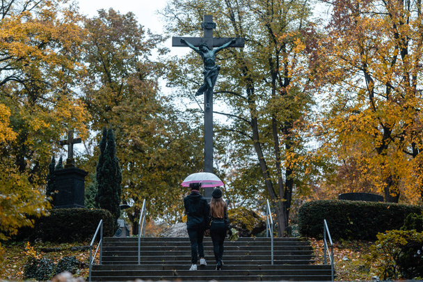 L'uomo e la donna che salgono i gradini del cimitero verso una croce
 - Foto, immagini