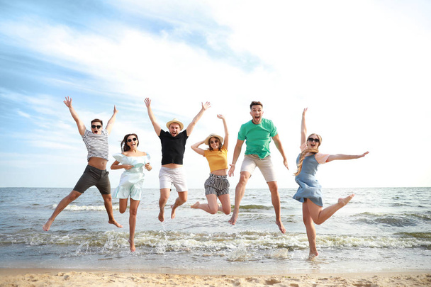 Happy jumping amigos na praia do mar no resort
 - Foto, Imagem