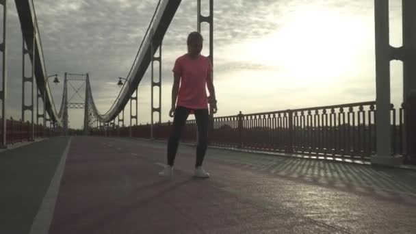 The girl warms up before jogging. The lady spends time outdoor alone. The woman leads a healthy lifestyle. Female turns her body in different sides and prepares to run - Imágenes, Vídeo