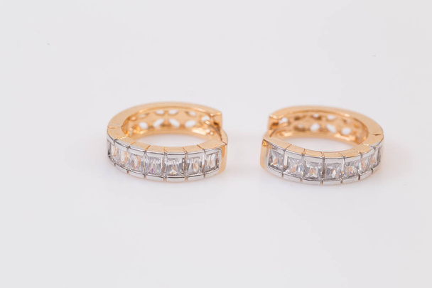 Ohrringe. Goldene Ohrringe mit Diamanten auf weißem Hintergrund. - Foto, Bild