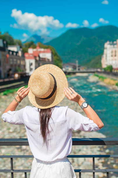 Chica feliz en el sombrero en el terraplén de un río de montaña en una ciudad europea
. - Foto, imagen