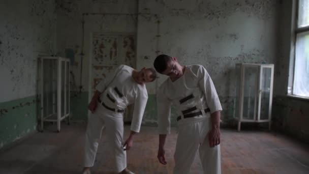 Dwa KOOK mężczyźni tańczą powoli i zginania do siebie w lepki pokój w SLO-mo - Materiał filmowy, wideo