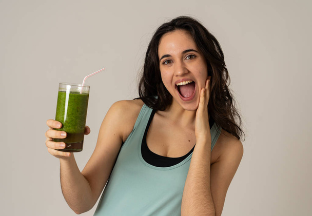 Fitness woman happy smiling holding glass of green vegetable smoothie after running or workout. Portrait isolated with copy space. Beauty Health Fitness Diet Nutrition and healthy Lifestyle concept. - Foto, immagini