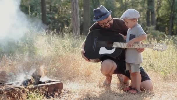 Otec a jeho syn s kytarou piknikem v lese - Záběry, video