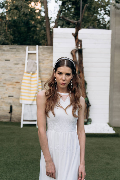 stylish woman in white dress looking at the camera and standing on the yard outdoors  - Fotografie, Obrázek