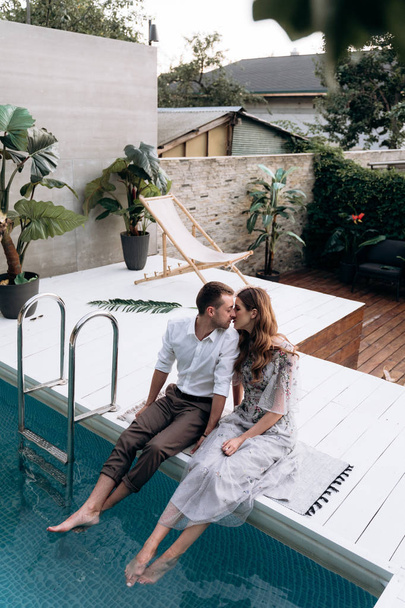 overhead view of young man and woman sitting at the swimming pool - Foto, Imagen