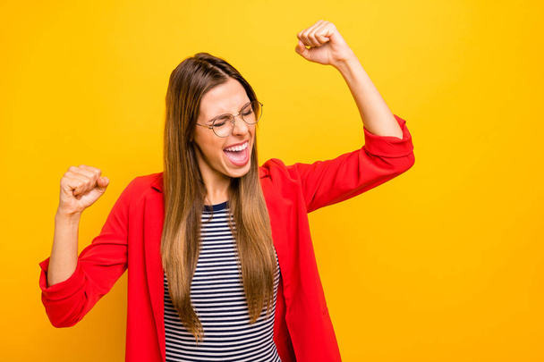 Portrait of cheerful lady raising her fists screaming shouting yeah wearing red striped shirt isolated over yellow background - Fotoğraf, Görsel