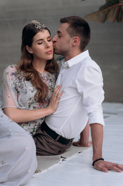 man kissing attractive woman sitting on white wooden stage outdoors  - Foto, afbeelding