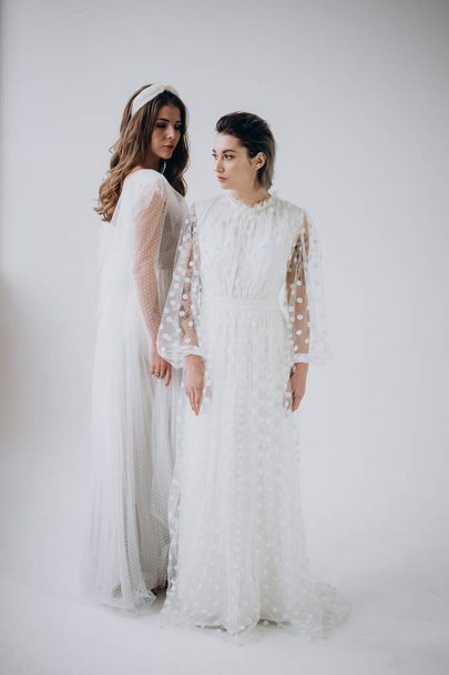 Full Length of two models wearing white dresses posing  on light background, studio shot  - Photo, Image