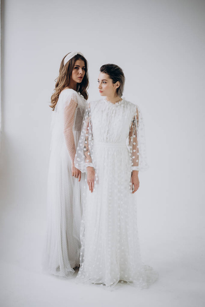 Full Length shot of two models wearing white dresses posing  on light background, studio shot  - Фото, зображення