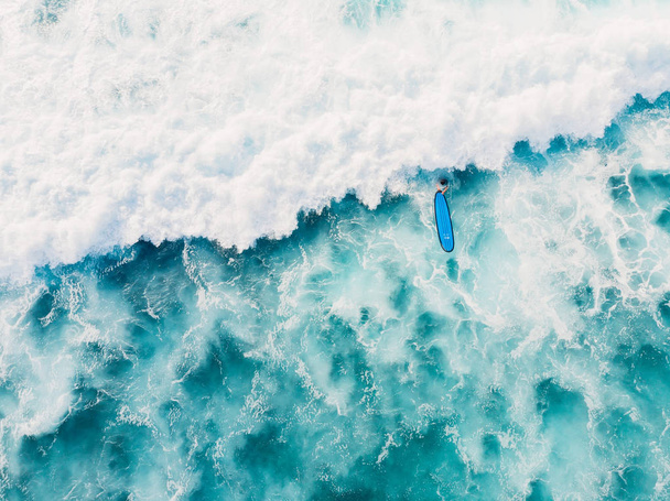 Вид с воздуха на серфера и волну в океане. Вид сверху
 - Фото, изображение