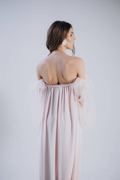 back view  of woman wearing dress in boho style  standing on light background  - Foto, afbeelding