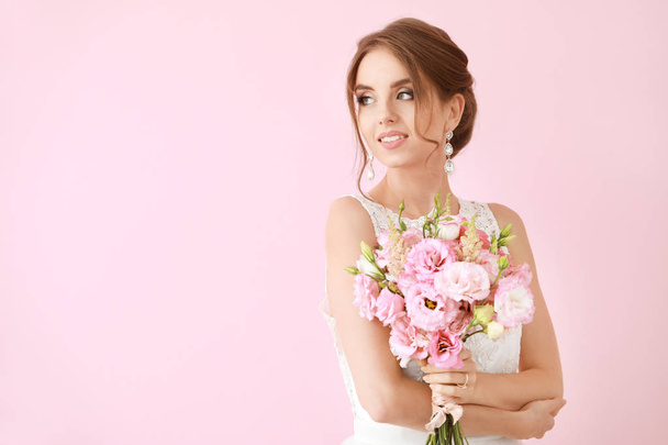 Portrait of beautiful young bride with wedding bouquet on color background - Photo, Image